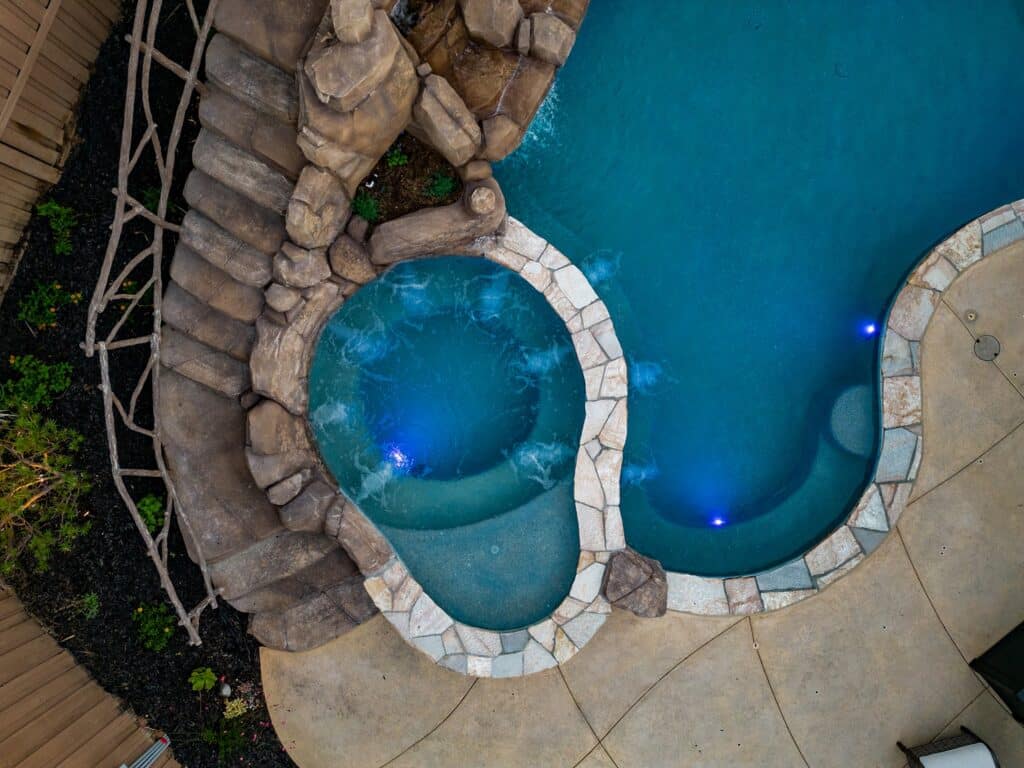 Custom backyard pool with a hot tub and water slide