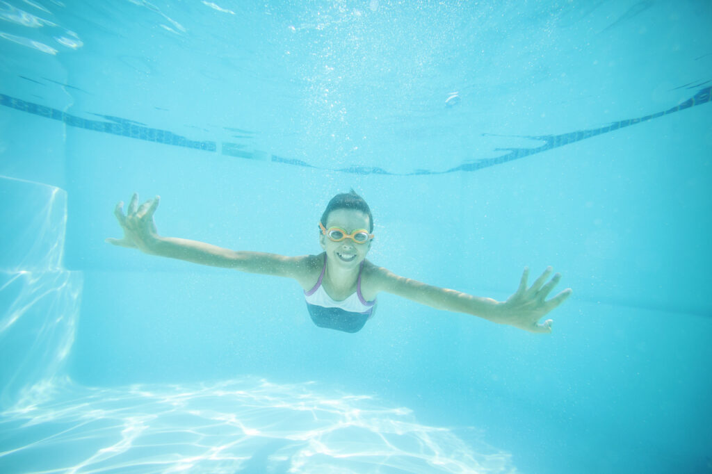 joyful girl swimming underwater in residential pool