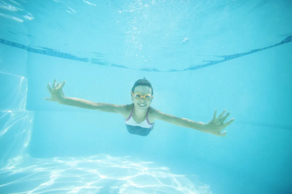 joyful girl swimming underwater in residential pool