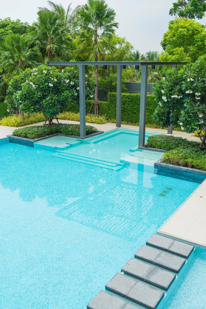 Modern custom swimming pool with landscaped surroundings, showcasing elegant pool design and features for homeowners planning to build a new pool